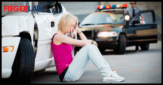 woman sitting next to vehicle after a crash