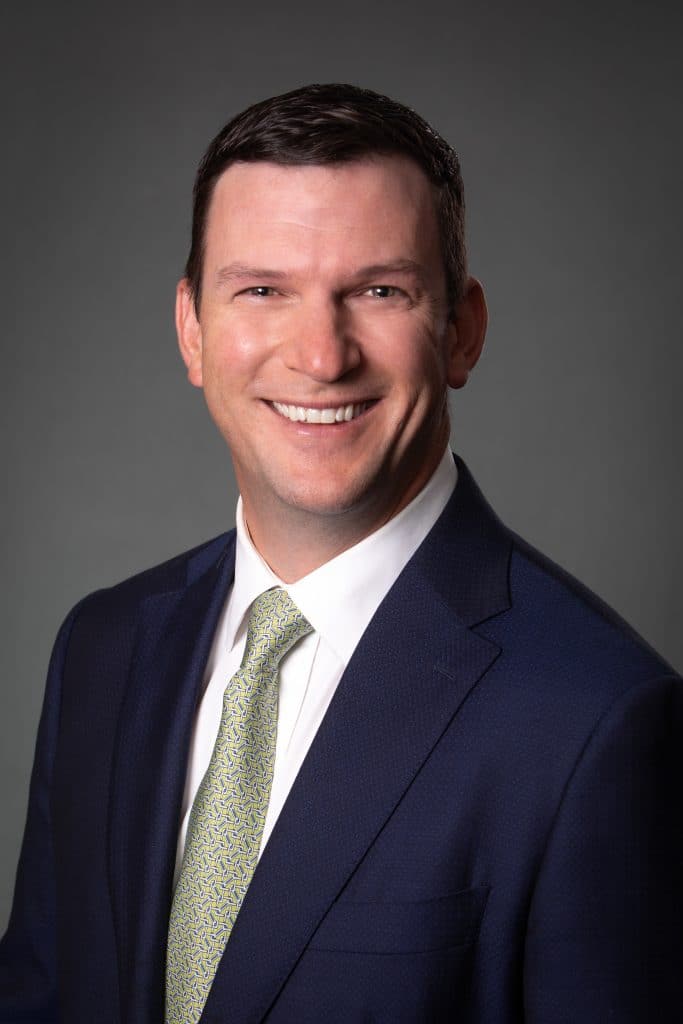 a man wearing a suit and tie smiling at the camera