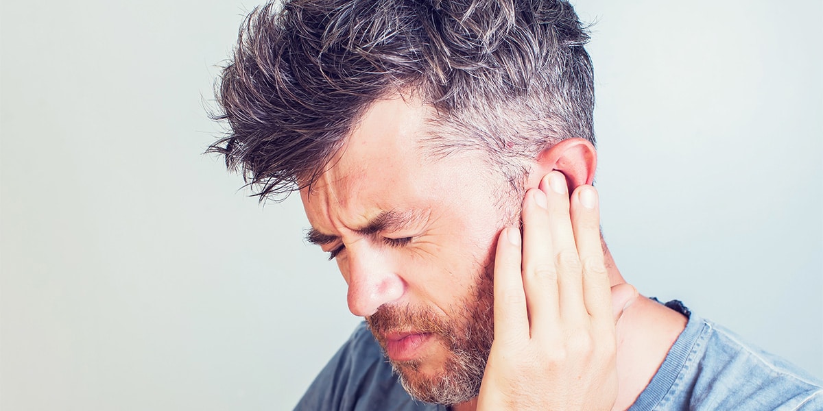 Image of man holding his ear in pain.
