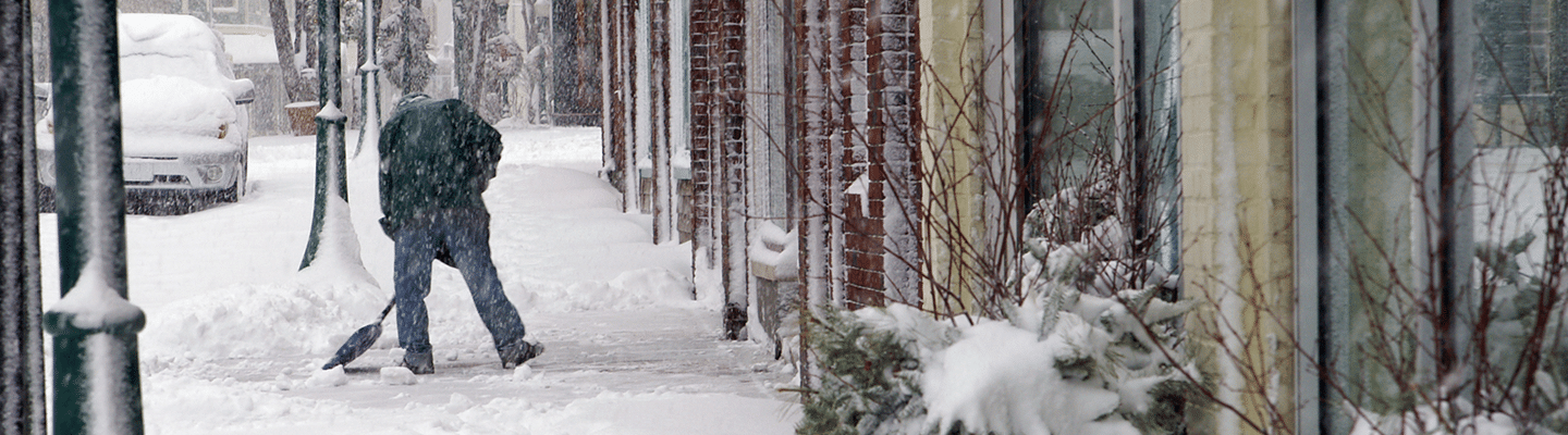 A man shoveling snow outside a business's door