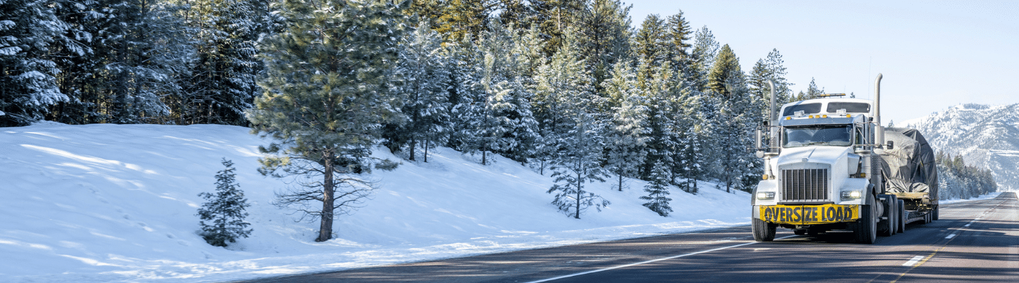 Image of a semi-truck traveling down a snow covered road