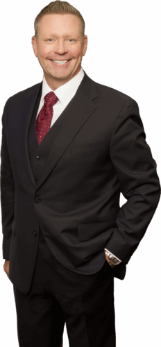 Smiling man in a dark suit and red tie, posing confidently indoors.